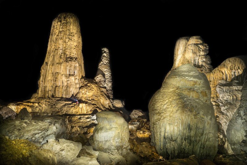 Гигантские сталагмиты кажутся исполинами рядом с маленьким человеком. Сталагмиты — натёчные минеральные образования, растущие в виде конусов, столбов со дна пещер.