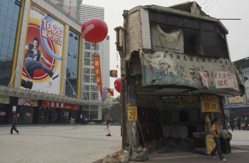 В городе Чанша (провинция Хунань) на площади перед современным торговым центром из стекла и бетона стоит ветхая двухэтажная постройка, хозяева которой не желают переселяться