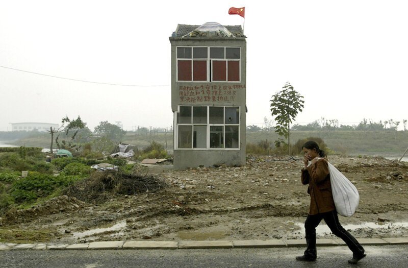 Девушка идет мимо последнего старого дома в одном из районов на окраине Нанкина в провинции Цзянсу
