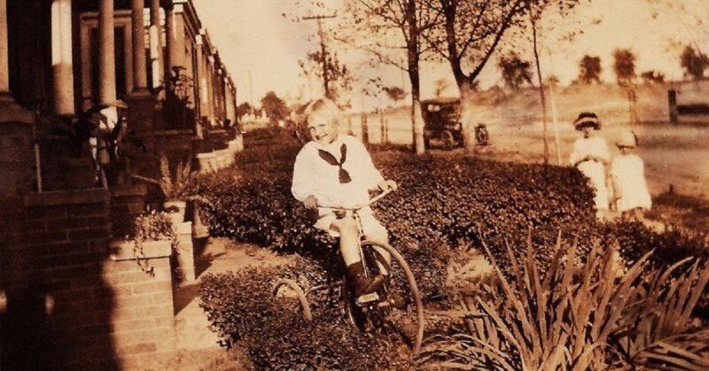 Мальчик на трехколесном велосипеде перед своим домом в Куинсе