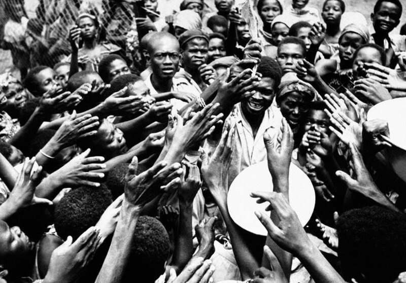 Люди тянутся к представителю правительства, раздающему вяленую рыбу и пальмовое масло людям в больнице в Миаби, Конго, 26 января 1961 года. 
