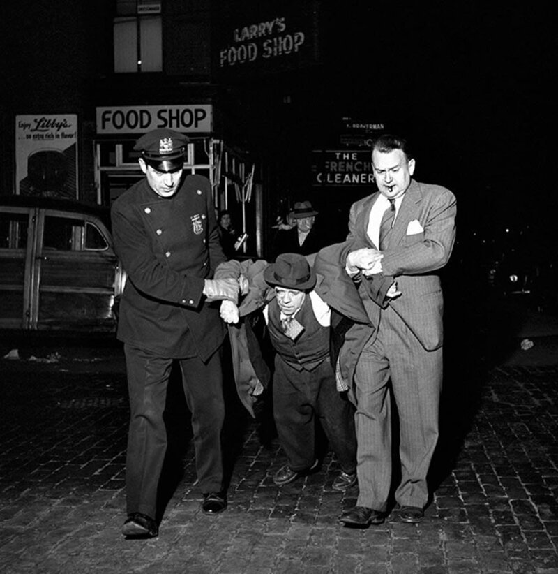 Пьяного избитого мужчину несут в участок в канун Рождества. Нью-Йорк, штат Нью-Йорк ,США. Декабрь 1953. 