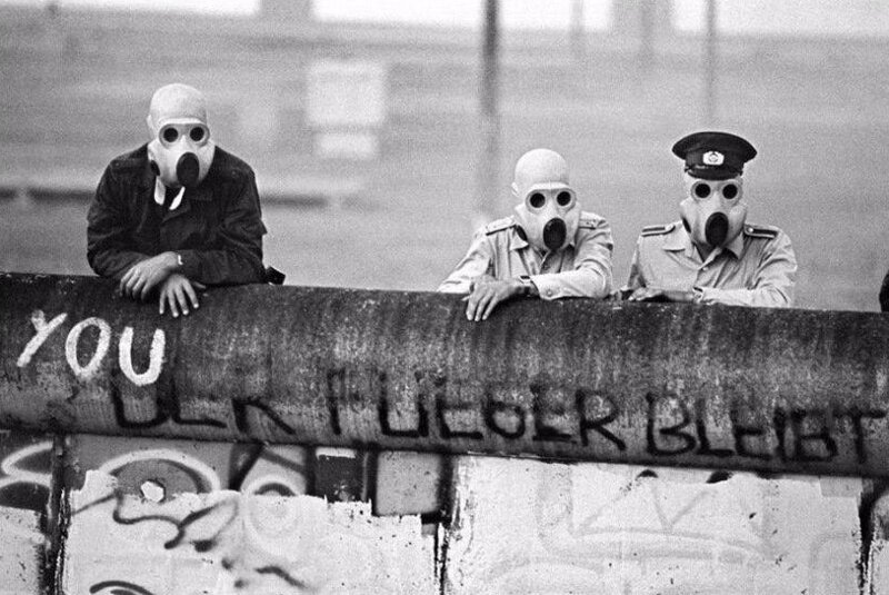 Пограничники с берлинской стены смотрят как демонстрантов разгоняют слезоточивым газом, 1988 г. 