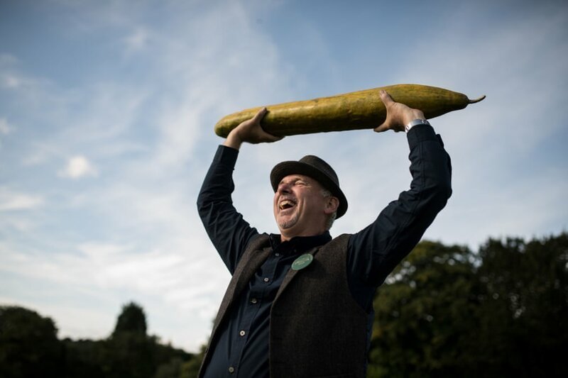 Грэм Барратт держит в руках свой 92-сантиметровый огурец, который получил первый приз в категории самых длинных огурцо