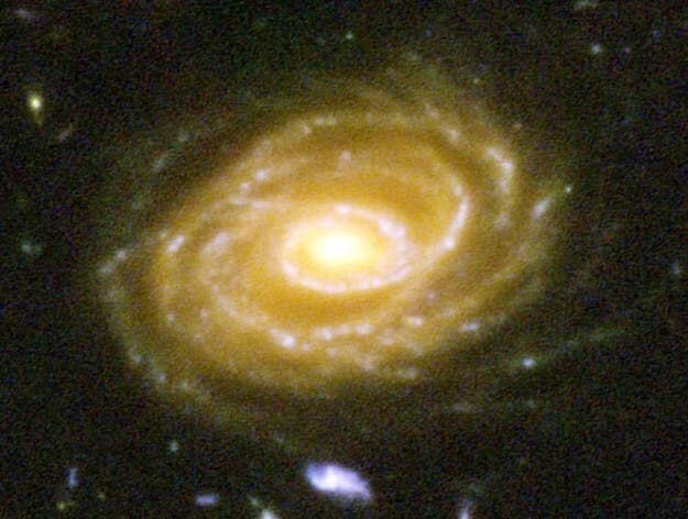 Это - галактика UDF 423. Она находится в миллиардах световых лет от Земли. Глядя на нее, вы смотрите на миллиарды лет в прошлое