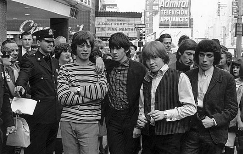 Мик Джаггер, Кит Ричардс, Брайан Джонс, Чарли Уоттс и Билл Уайман из «Роллинг Стоунз» фотографируются на нью-йоркской улице, а полицейский сдерживает любопытных зрителей. Июнь 1964 года 