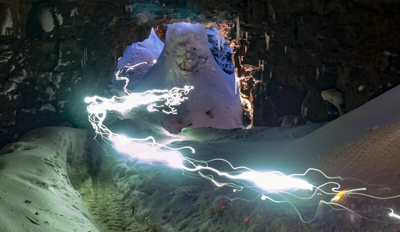Налобные фонари многочисленных путешественников, приезжающих посмотреть на лавовую пещеру, превращают ее в реку огней