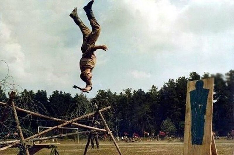 Тренировка советского спецназа. В прыжке с переворотом солдат успевает метнуть топорик в мишень. 
