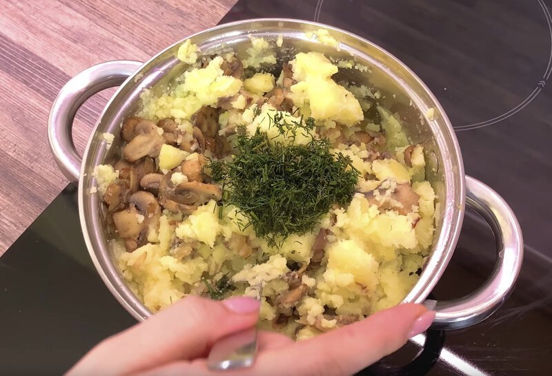 Сваренный картофель толчем и добавляем к нему лук с грибами, по вкусу добавляем укроп