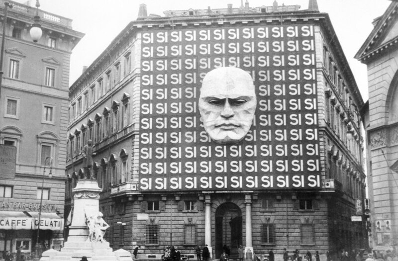 Пропагандистский плакат с портретом Бенито Муссолини и сотней слов Si на фасаде палаццо Браски,где размещался офис фашистской партии,апрель 1934 года.В настоящее время размещается Музей Рима.