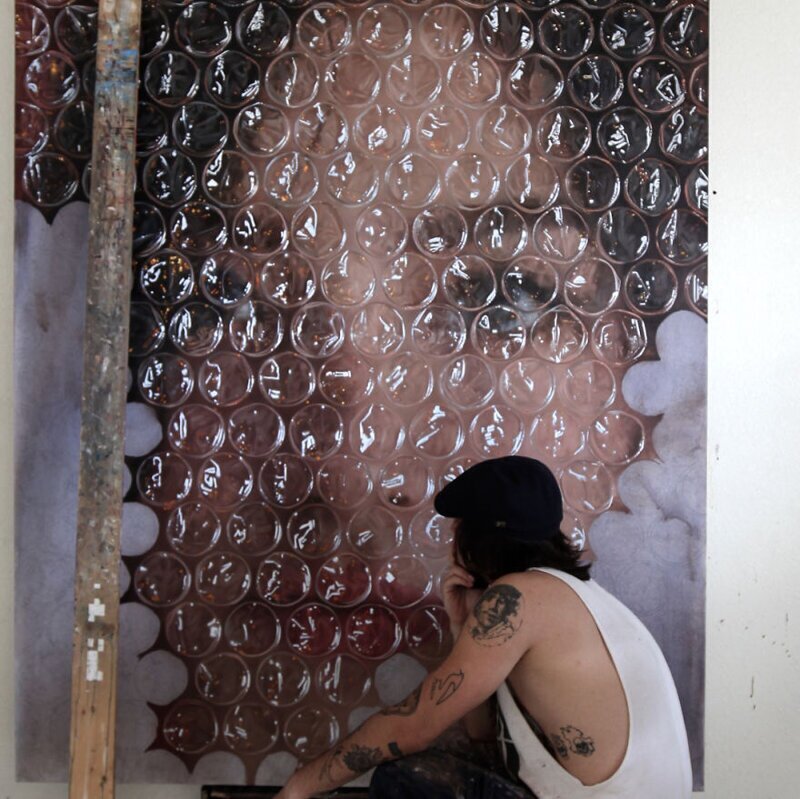 Художник рисует портреты, которые как-будто бы завёрнуты в пузырчатую плёнку 