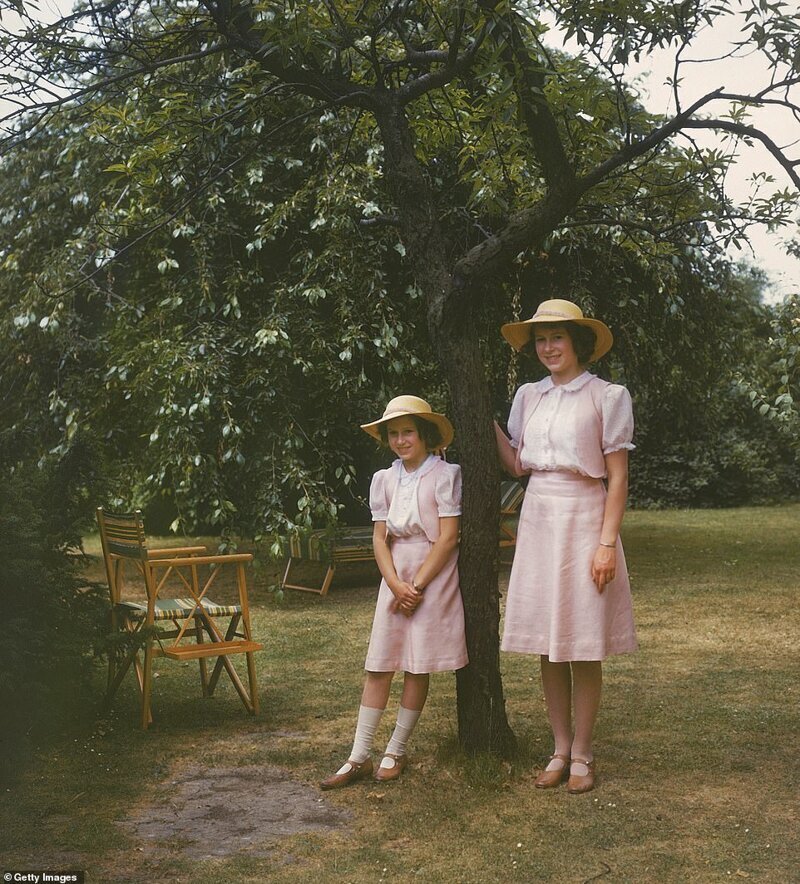 Одеты как близнецы: Елизавета и ее десятилетняя сестра в Виндзоре в июле 1941 года в одинаковых розовых юбках, топах болеро, шляпках от солнца и коричневых туфлях "Мэри Джейн"