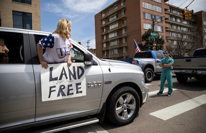 2. "Земля свободных": работники здравоохранения стоят на улице в знак протеста против бунта сотен людей, которые требуют отменить карантин