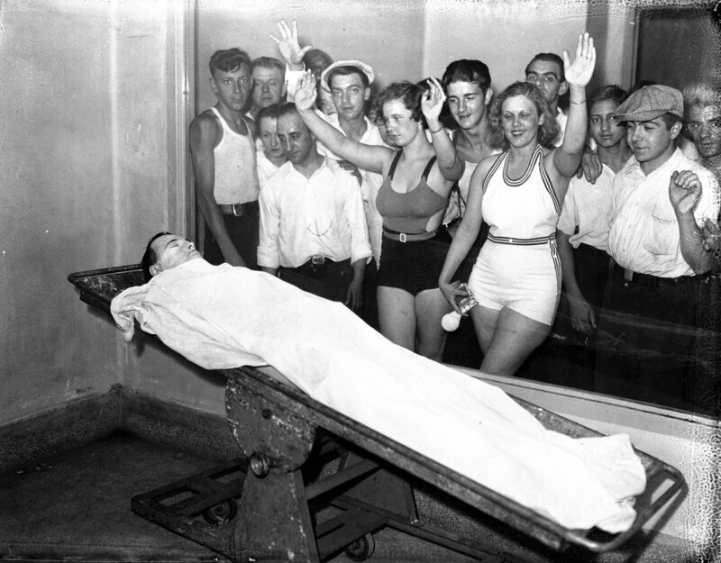 Простые американцы фотографируются с телом известного преступника, грабителя банков Джона Диллинджера, выставленном в морге для зрителей после его казни, 1934 г.