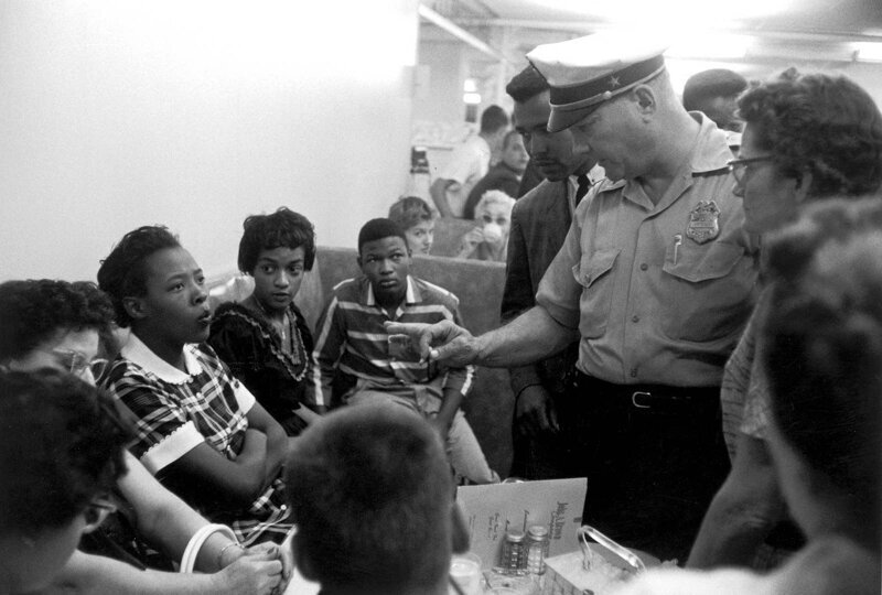 Офицер полиции разговаривает с чернокожими протестующими во время сидячей забастовки в кафе в Оклахоме, 1958 год