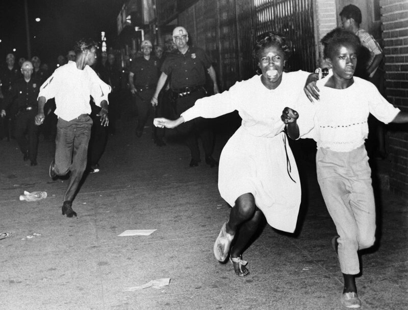 Две чернокожие девушки бегут от полицейских во время беспорядков в районе Бедфорд-Стайвесант в Бруклине, 21 июля 1964 года