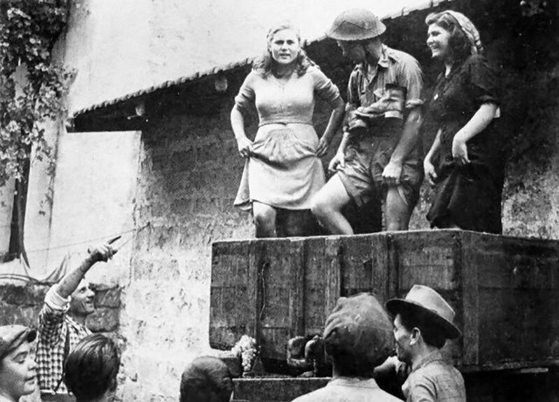 Солдат британской армии помогает жителям Кастель-Вольтурно под Неаполем давить виноград ногами, Италия, 1943 год