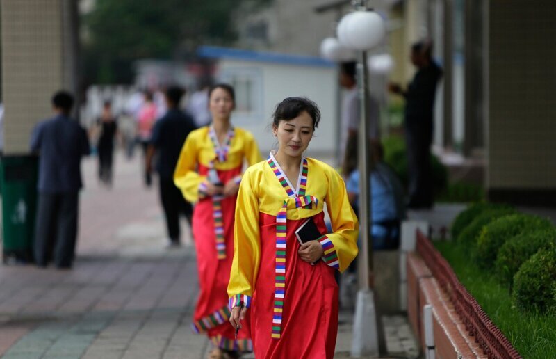 Северокорейские женщины-продавцы идут по улице в Пхеньяне.