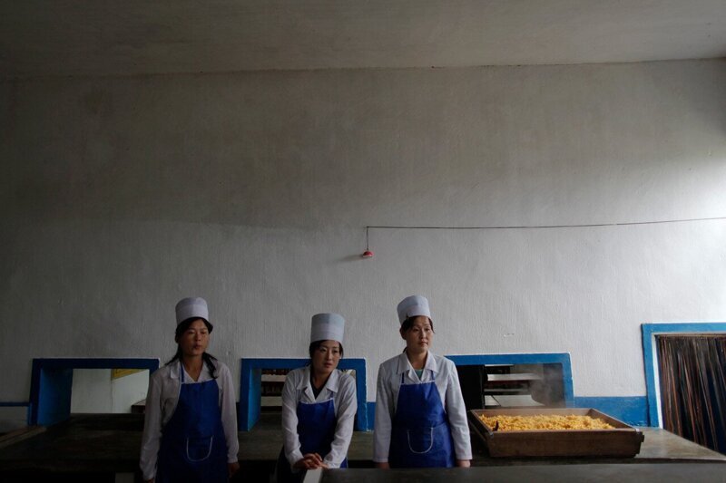 Северокорейские женщины стоят на раздаче кукурузной каши, приготовленной для детей-сирот в провинции Северный Хванхэ.