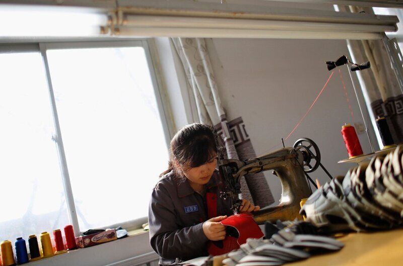 Северокорейская девушка работает на обувной фабрике в деревне Дандон.
