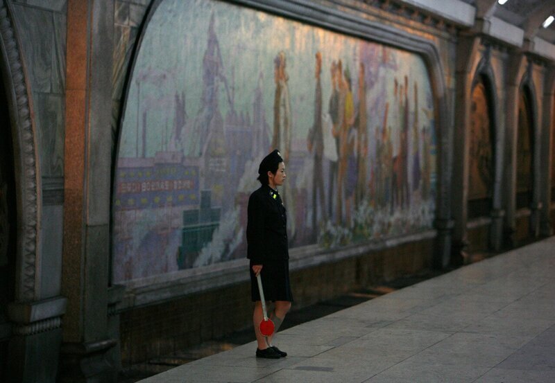Северокорейская работница метро ожидает поезда на станции метро в Пхеньяне: