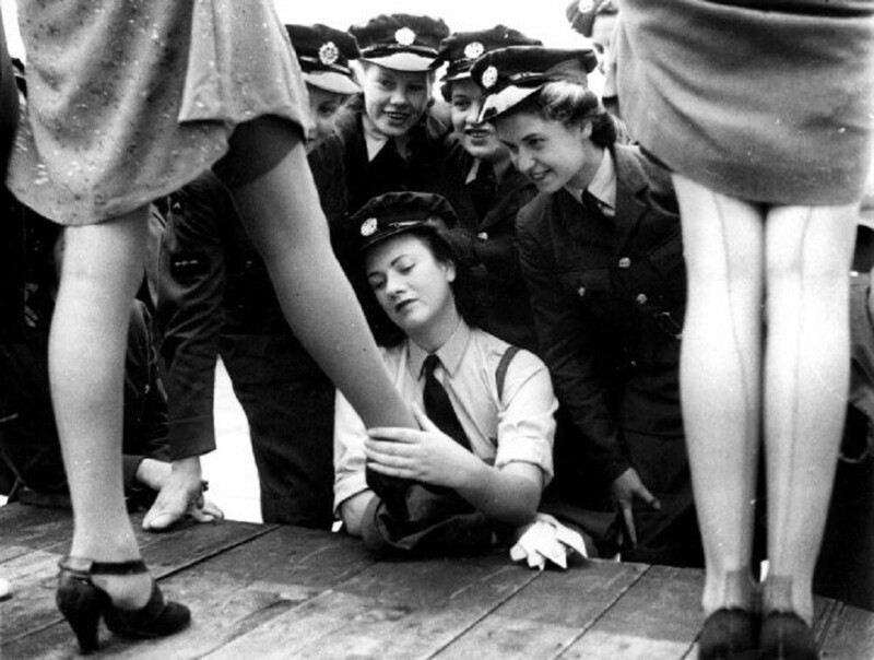 Женщины-военнослужащие рассматривают чулки из искусственного шелка, специально разработанные для армии, на показе мод в Лондоне, Великобритания, 1943 год