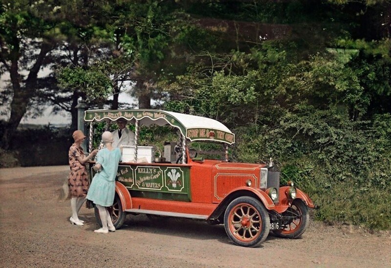 Две женщины покупают мороженое у продавца из преобразованного в ларёк автомобиля в Корнуолле. Мороженое Kelly's производят по сей день.  Фотограф Клифтон Р. Адамс (Clifton R.Adams). 1928. Автохром