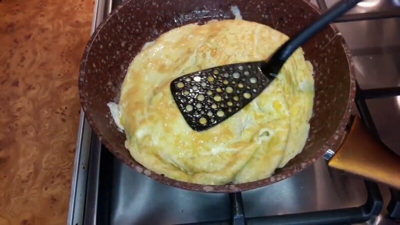 Когда яйца обжарились с одной стороны, переворачиваем омлет на другую сторону.