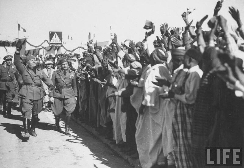 Муссолини приветствует местных мусульман встречающих его во время его визита.