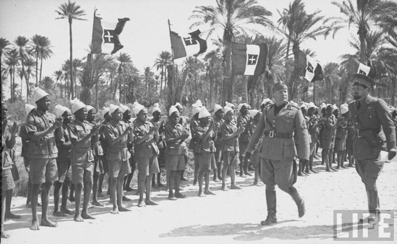 Бенито Муссолини обходит группу арабских мальчиков в форме во время своего визита в Триполи