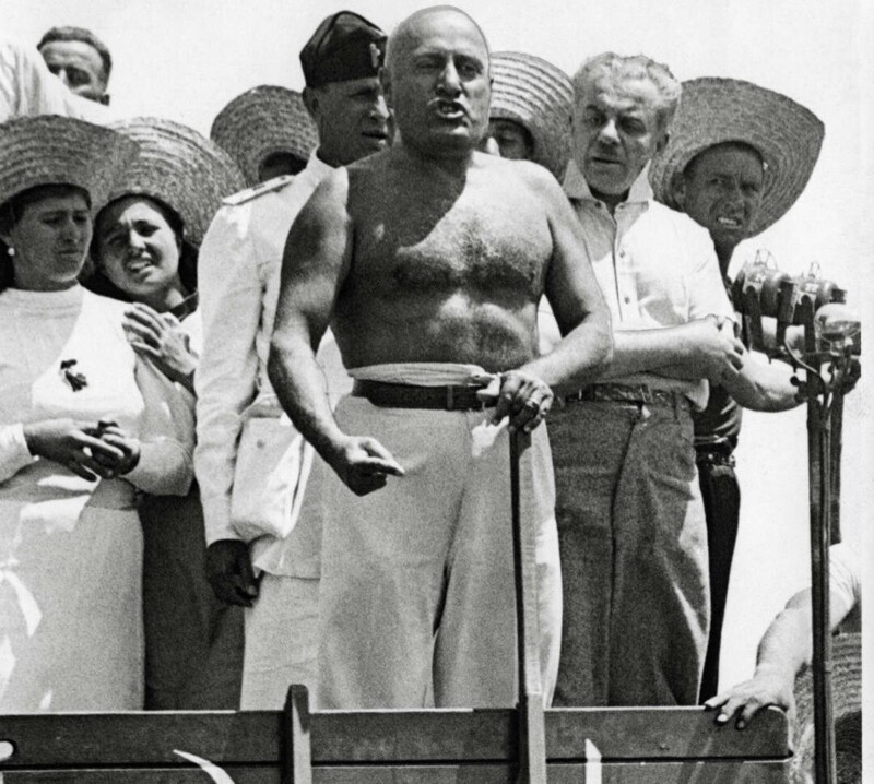 Окруженный сельскохозяйственными рабочими Бенито Муссолини демонстрирует голый торс. 1938