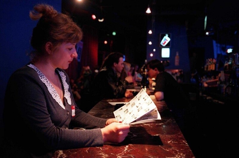 Незамужняя женщина просматривает каталог подходящих американских холостяков на вечере встреч, организованном брачным агентством в ночном клубе «Manhattan Express», 4 апреля 1997 года.