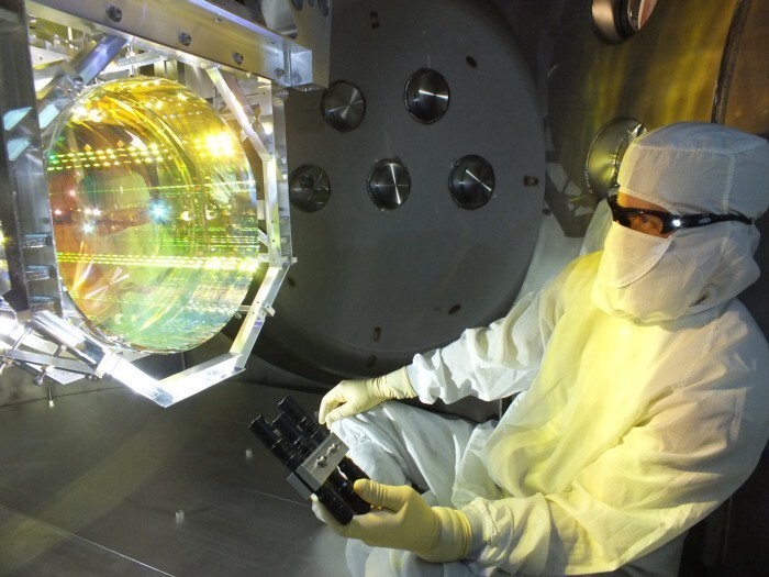 Техник внимательно осматривает зеркала на объекте Ливингстона обсерватории LIGO. Посветив на инструмент лазером, можно определить пыль или другие загрязнения.