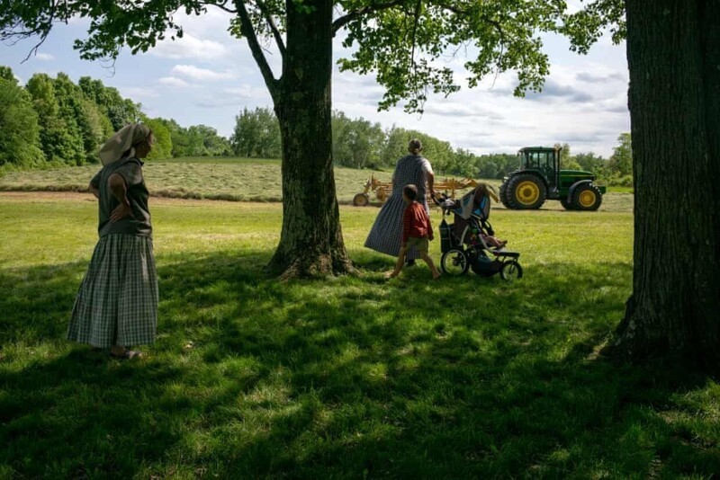 Семья наблюдает, как трактор обрабатывает поля на ферме в районе Фоксхилл.