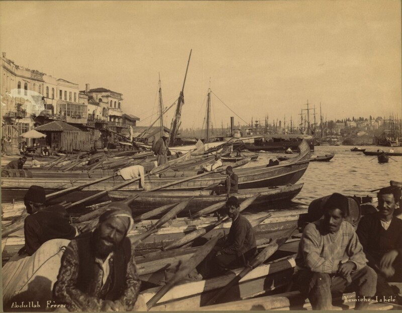 Мужчины сидят в лодках возле пристани Йемишь Искелеси