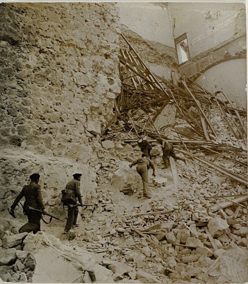 Франкистские солдаты идут по руинам Алькасара в Толедо летом 1936 года во время гражданской войны в Испании