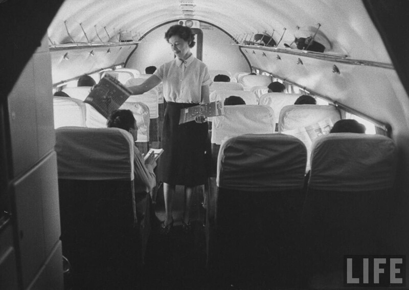 Стюардесса раздает журналы пассажирам на борту самолета