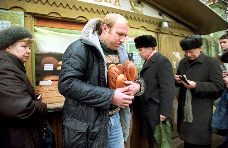 1992. 3 ноября. Мужчина уходит от хлебного киоска с несколькими буханками хлеба. Доллар США в настоящее время стоит 398 рублей, а средняя месячная зарплата в России составляет примерно 5000 рублей (12 долларов США) в месяц.