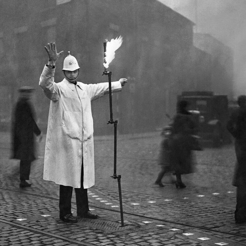 12. Полицейский управляет движением в лондонском тумане с помощью факела, 1935 год