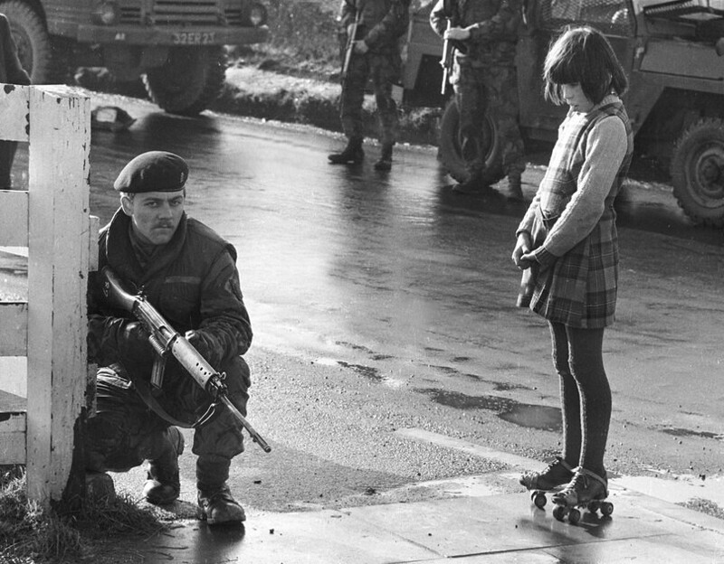 Любопытная девочка наблюдает за действием армейского патруля; Северная Ирландия; 1969