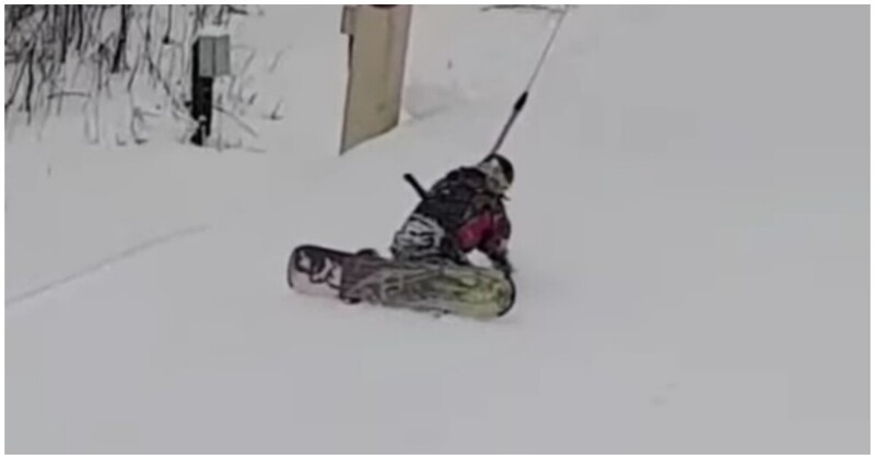 Начинающий сноубордист пытается справиться с бугельным подъемником