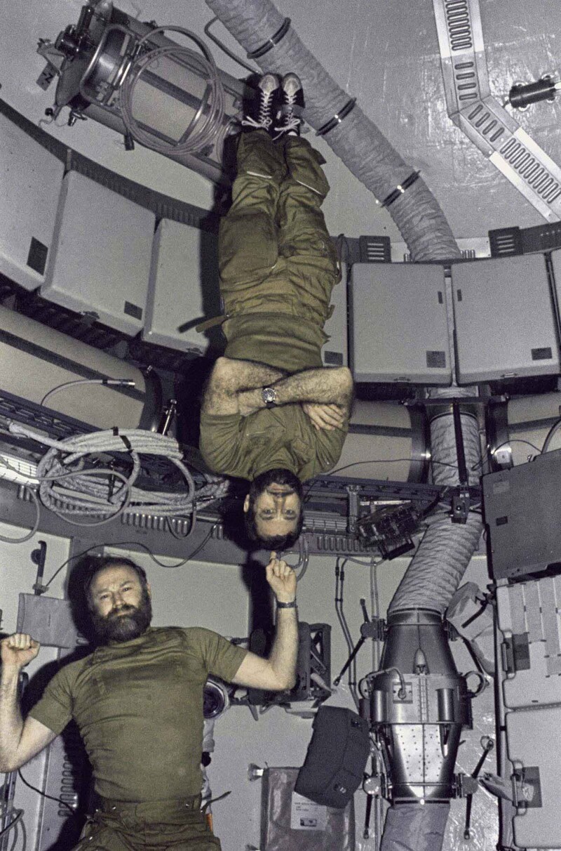 Джеральд П. Карр, командир миссии Skylab 4, демонстрирует свою силу в условиях невесомости, подняв одним пальцем пилота Уильяма Р. Пога. 1974 г.