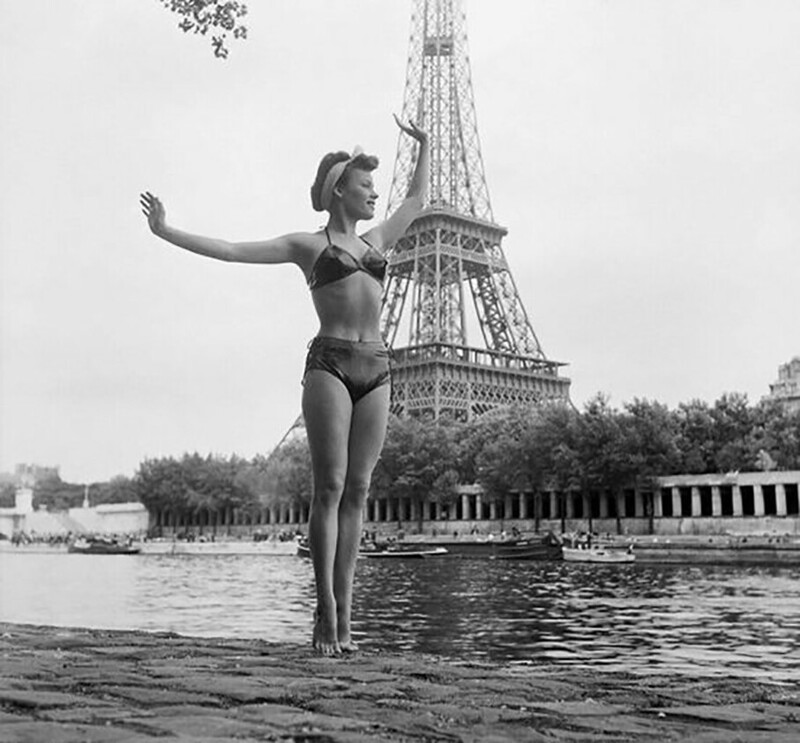 Женщина в купальнике позирует перед Эйфелевой башней на берегу Сены в июле 1949