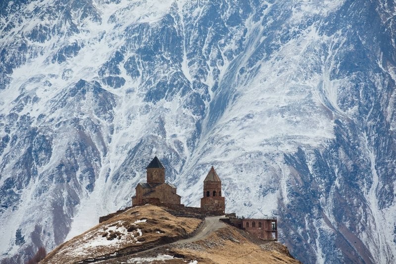 Вид на Троицкую церковь, расположенную в Грузии на фоне заснеженного горного склона Кавказского хребта