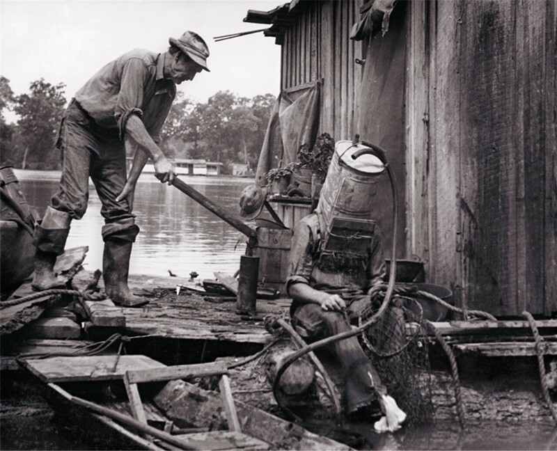Ловец жемчуга на Миссисипи готовится к очередному погружению. В качестве шлема - старый топливный бак от автомобиля. 1938 год