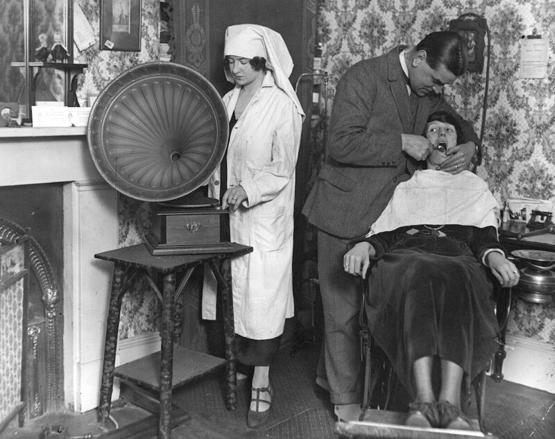 Помощница стоматолога заводит граммофон, чтобы отвлечь пациента от боли, это 1922 год.
