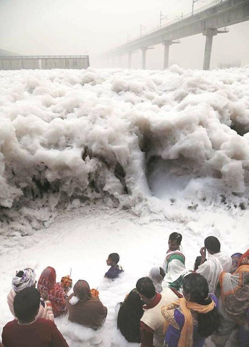 Люди возносят молитвы у реки Джамна, Индия, которая образует пену благодаря промышленным отходам