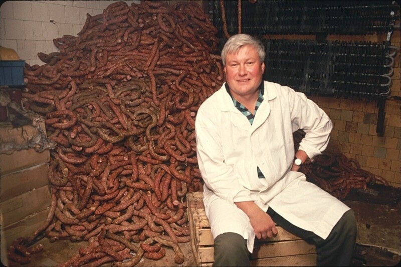 Колбасы по ГОСТу. Работник колбасного цеха на фоне своей продукции, 1991 год
