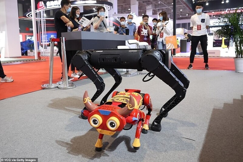 Четвероногие роботы гуляют у стенда Unitree Robotics. Маленький выполнен в виде бычка