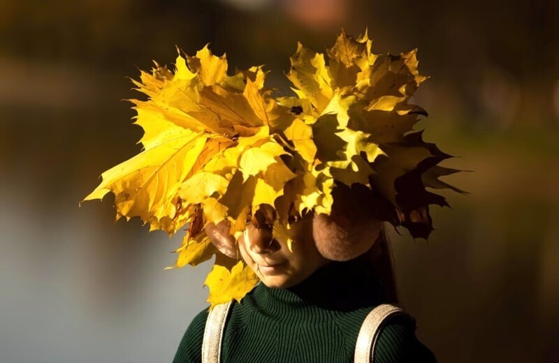 Девушка в венке из листьев гуляет в солнечную осеннюю погоду в Москве, Россия, 10 октября 2021 г.  